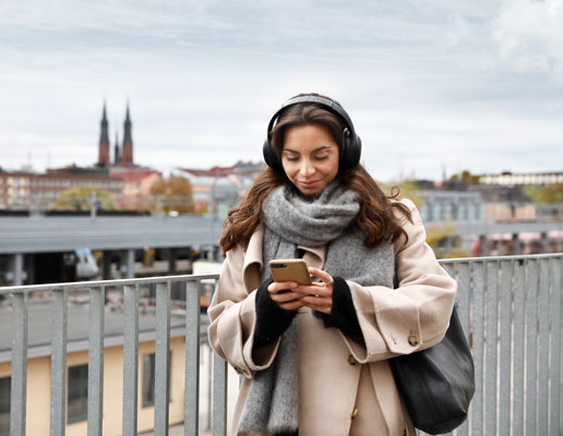 Kvinna utomhus som håller i en mobiltelefon