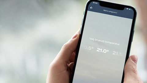 Hand som håller i en mobil där temperaturinställningar visas