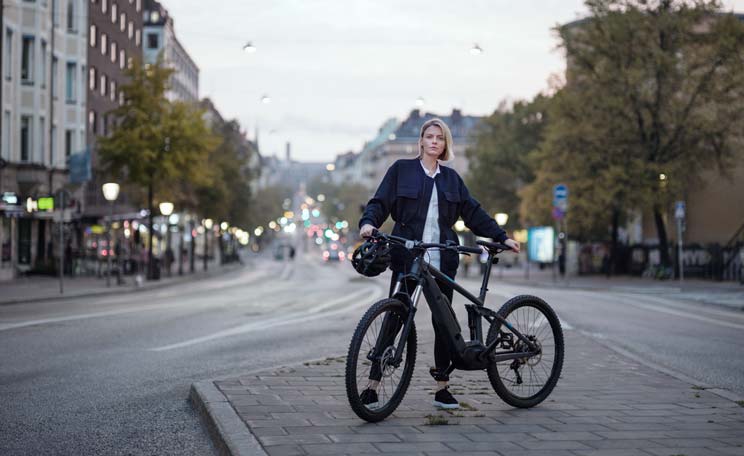 Kvinna med cykel på en stadsgata