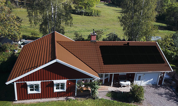 Rött hus med vita kanter med solceller på taket.