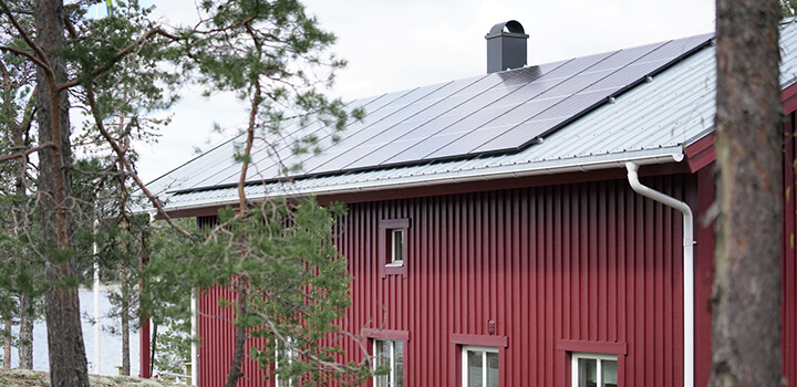 En röd stuga med solceller på taket